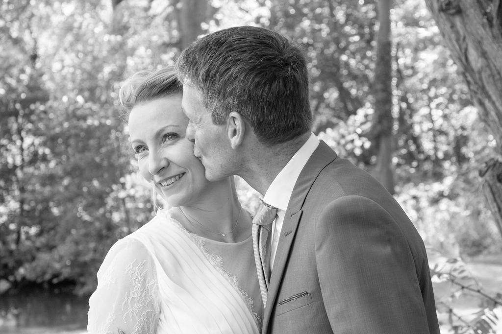 photo des mariés s'embrassant dans un parc noir et blanc