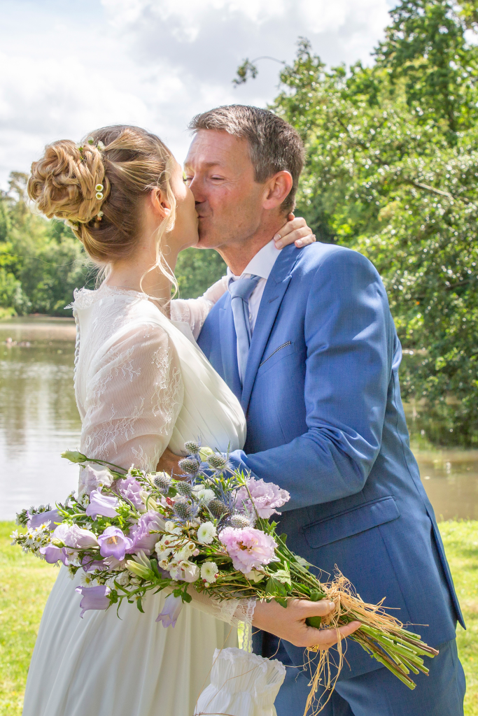 photo des mariés s'embrassant dans un parc 