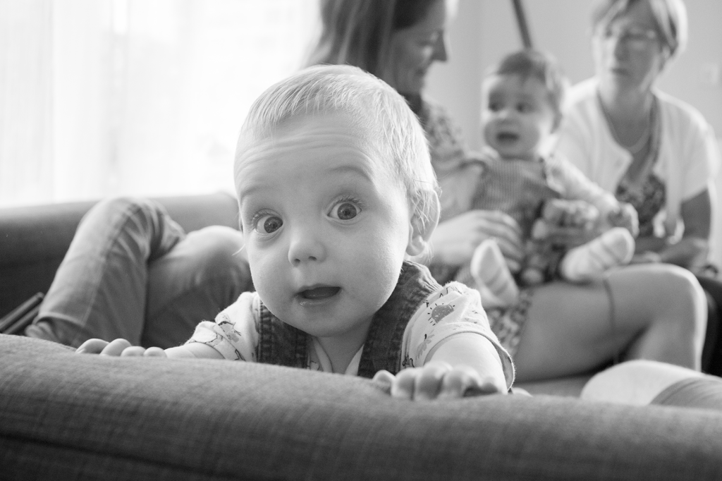 photo en noir et blanc d'un bébé jouant sur le canapé 