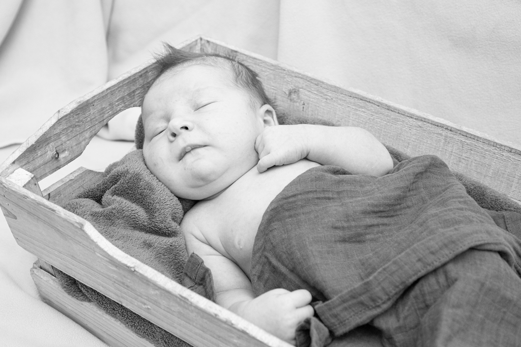 photo noir et blanc de maternité, bébé dans une caisse en bois en train de dormir