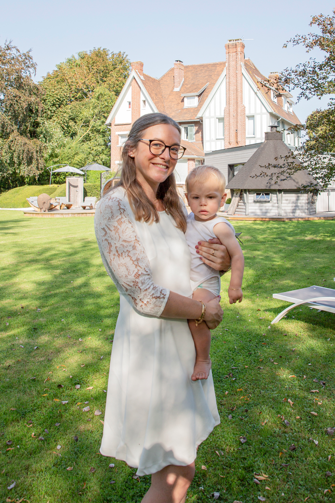 photo d'un mère avec son enfant dans les bras dans un jardin devant une maison