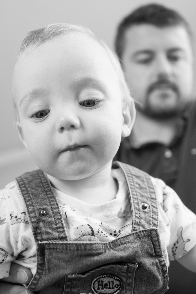 photo en noir et blanc d'un bébé avec avec son père en arrière plan