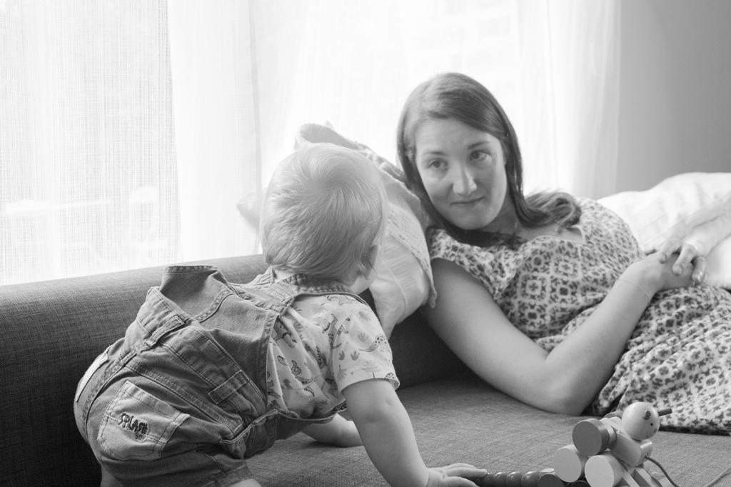 photo en noir et blanc d'une maman avec son bébé jouant sur le canapé