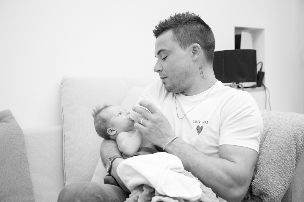 photo de maternité noir et blanc le papa et le bébé se regardent pendant le biberon 