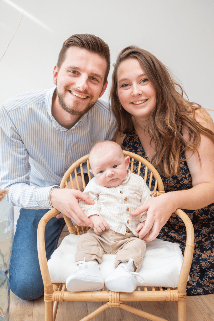 photo bébé assis sur une chaise avec ses parents derrière