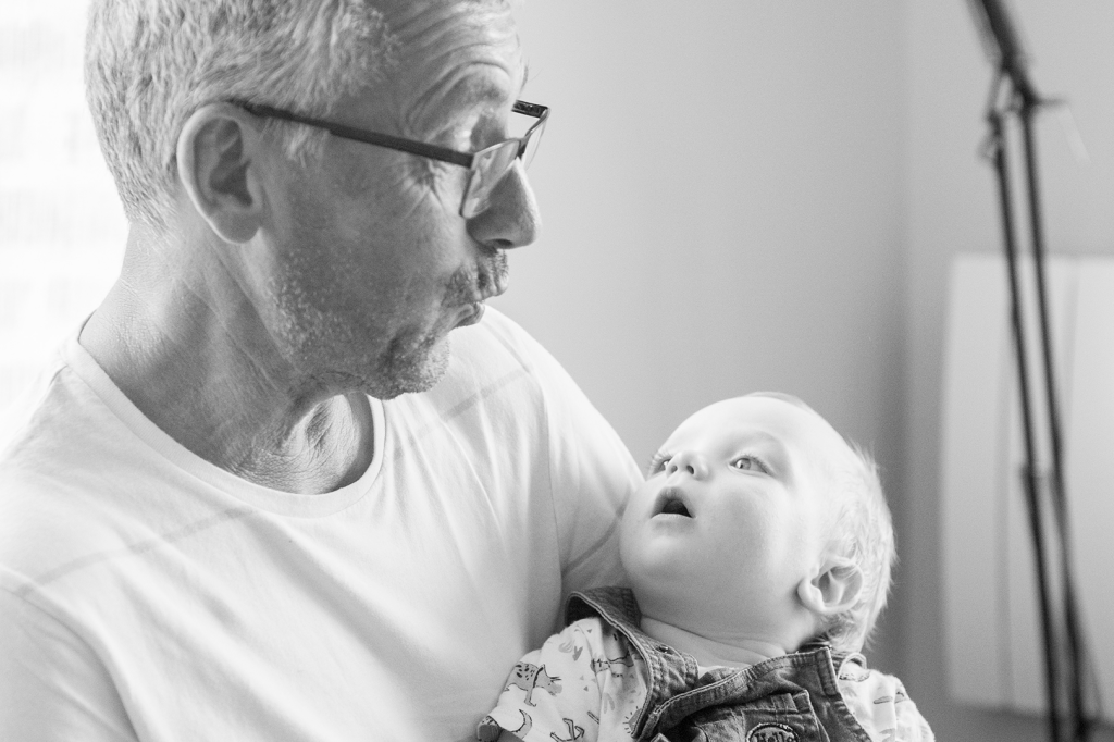 photo en noir et blanc d'un bébé jouant avec son grand père 