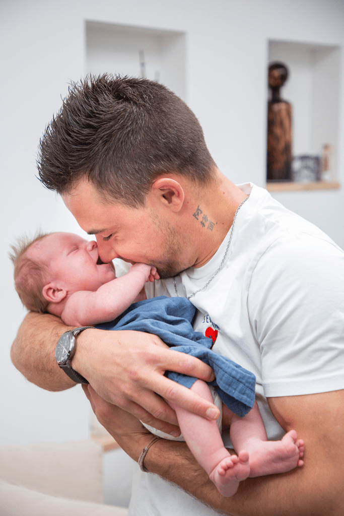 photo de maternité le papa rigole avec son fils dans les bras