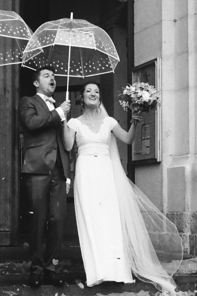 photo des mariés devant les portes de l'église en noir et blanc